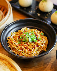 Dough Zone Dumpling House signature dishes Xiao Long Bao (Soup Dumplings), Q-Bao (Pan-Fried Pork Buns), Dan Dan Noodles, Spicy Wontons